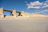 a large concrete structure with a long sidewalk underneath it, as if in an airplane port