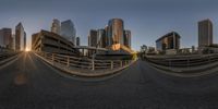 a cityscape image with no people in the street near the bridge, taken with a fisheye lens