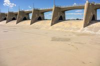 a bridge that is over the water in a desert area with sand on either side