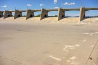 a man on a skateboard doing tricks in a cement lot under concrete bridges above