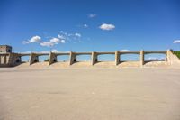 three concrete bridge on the ground with a building in the background, under a blue sky