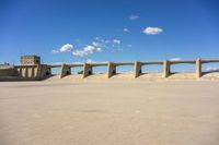 three concrete bridge on the ground with a building in the background, under a blue sky