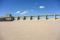 three concrete bridge on the ground with a building in the background, under a blue sky