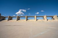 the concrete structure is all over with some clouds in the sky behind it and below it