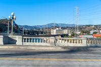 a view down a paved city street with some hills in the background near a bridge and water