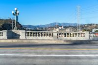 a view down a paved city street with some hills in the background near a bridge and water