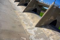 a view of the underside of an old concrete bridge from below, in which are four curved pillars