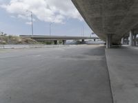 the view from under a bridge of a roadway and a road underneath it, which is empty