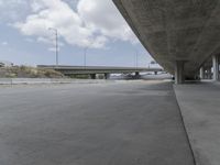 the view from under a bridge of a roadway and a road underneath it, which is empty