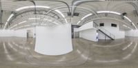 a panorama photo of a long hallway of a building with curved ceilings and arches of varying height