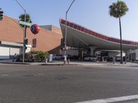 an open area near a building with cars stopped at a stop light and on the street near trees