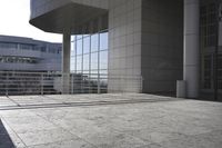 an open concrete courtyard with large windows and buildings reflecting in the windows and light in the afternoon