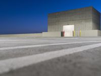 a small building with no doors is on the concrete flooring and some lines painted out