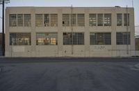 a white building with windows with graffiti on the sides of it is standing on the side of a road