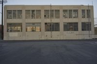 a white building with windows with graffiti on the sides of it is standing on the side of a road
