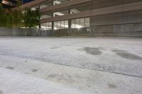 a large empty concrete area next to a building at night on a cloudy night time