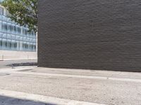 a man in white shirt using red fire hydrant next to black brick wall and sidewalk