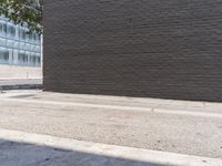 a man in white shirt using red fire hydrant next to black brick wall and sidewalk