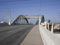 a large bridge over a road under a blue sky and wispy clouds in the distance