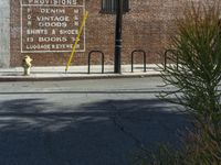 a side view of a brick building and some signs on it's side shows people are walking down the sidewalk