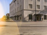 a building with people walking across the street in front of it on a sunny day