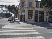 a car and person standing at an intersection on a city street with buildings in the background