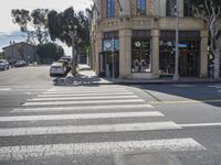 a car and person standing at an intersection on a city street with buildings in the background