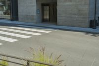 a crosswalk with zebra lines is in front of a grey building, which is also called a hotel