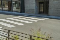 a crosswalk with zebra lines is in front of a grey building, which is also called a hotel