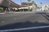 a street with palm trees and a red canopy on a building over the road and traffic lights