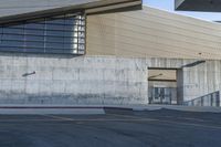 a person riding a skateboard on the sidewalk near an entrance ramp in a large building