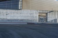 a person riding a skateboard on the sidewalk near an entrance ramp in a large building