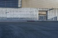 a person riding a skateboard on the sidewalk near an entrance ramp in a large building