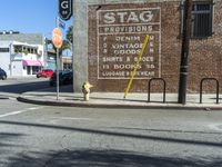 a yellow fire hydrant on a sidewalk in front of a building with the stag provisions sign written on it