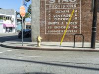 a yellow fire hydrant on a sidewalk in front of a building with the stag provisions sign written on it