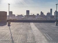 a view of the city across the parking lot from an empty parking lot with the sun on the horizon