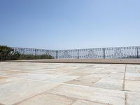 an empty patio in front of a railing and lake view looking out onto the water