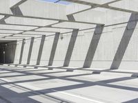 the walkway is made from concrete and has multiple beams above it with blue sky and trees