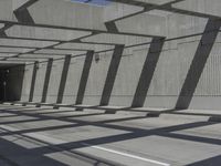 the walkway is made from concrete and has multiple beams above it with blue sky and trees