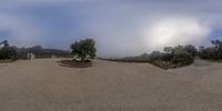 two houses are visible behind a stone wall on a cloudy day, one is a circular panorama view