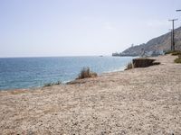 the shoreline of a beach next to a body of water with boats in the distance