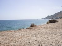 the shoreline of a beach next to a body of water with boats in the distance