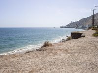 the shoreline of a beach next to a body of water with boats in the distance