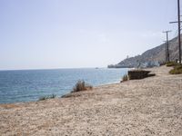 the shoreline of a beach next to a body of water with boats in the distance