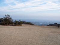 a man sits on top of a hill overlooking the city of los angeles, california