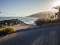 a lone motorcyclist passes along the beach line as the sun sets in the background