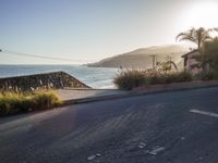 a lone motorcyclist passes along the beach line as the sun sets in the background