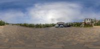 a driveway with an empty car and buildings in the background, as seen from a fish eye view point on a fish - eye lens