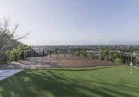 this is an image of a large artificial putting green for a golf course with the view over trees in the distance