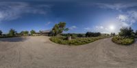 three houses are featured with a dirt road in front of them and a large grassy field to the left